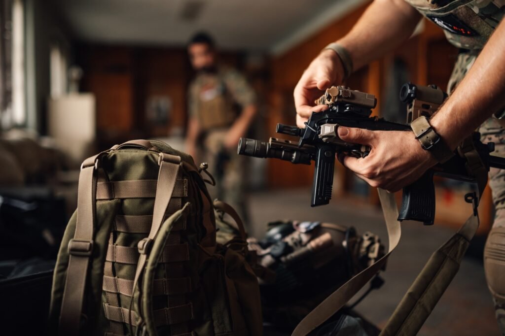 Close up of airsoft fighter's hands holding rifle and putting battery on
